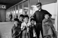 Vijf Vietnamese adoptiekinderen met een jonge priester aan de luchthaven, op weg naar België, 1975.